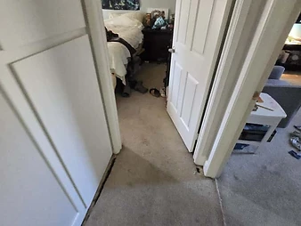Bedroom viewed from hallway with forest tapestry on wall and ceiling inspection cutout visible