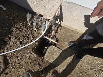 Exposed sprinkler and irrigation valve manifold connected to PVC piping in an excavated trench