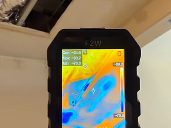 F2W thermal imaging camera showing wall cavity heat map with cool blue moisture regions and crosshair markers