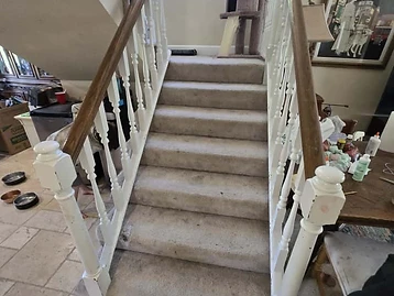 Interior staircase with stained glass window, soiled carpet, and woodwork showing wear from water damage