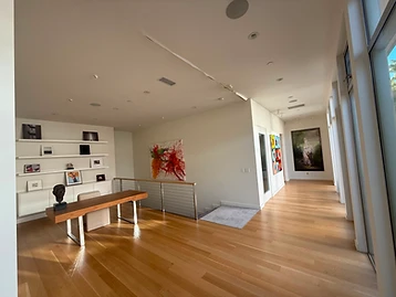 Open-plan living space with a jagged ceiling crack running across the drywall, near a staircase with cable railing