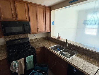 Kitchen with oak cabinets, black appliances, granite countertops, and two XPOWER air movers on the floor with blue tape markings on ceiling
