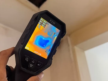 F2W thermal imaging camera showing heat map of wall surface with cool blue moisture patch at 82.8 degrees F