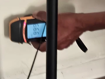 Technician using a digital moisture meter to test water content in an interior wall during damage assessment