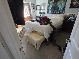 Bedroom during restoration inspection with wall-mounted TV, bed, and ceiling access panel visible