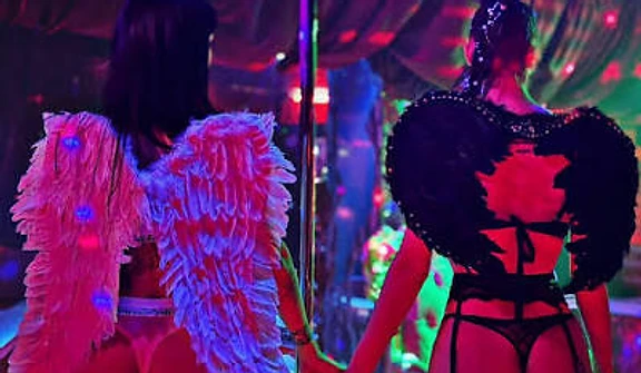 Two performers in feathered wings standing back to back by the pole