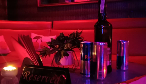Reserved table with candle, sign and drinks under red light