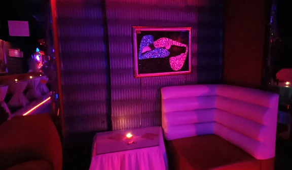 Curved white booth bathed in magenta light with a glowing candle