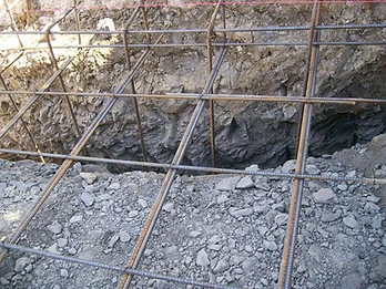 Close-up of steel rebar grid tied with wire in an excavated trench with red alignment string line above