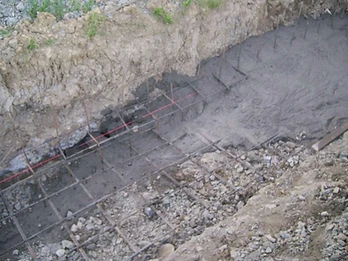 Excavated foundation trench with horizontal rebar grid and red alignment string line