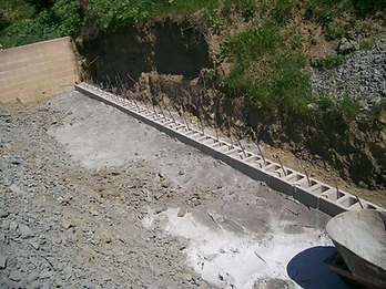 Concrete masonry units laid in a trench with vertical rebar pins for a retaining wall foundation