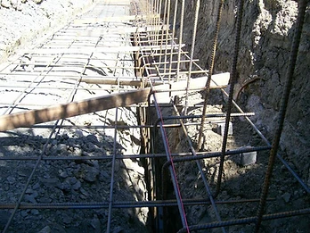 High-angle view of steel rebar grid installed in a foundation trench with vertical dowels and pink masonry string line