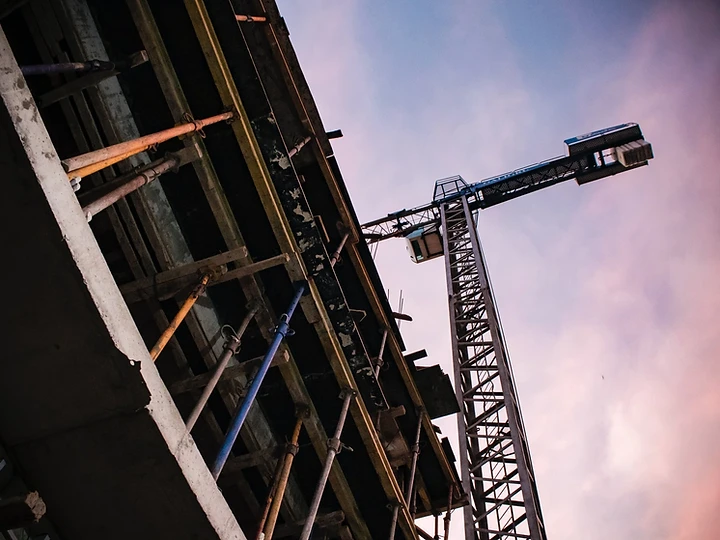 Construction worker and crane silhouetted against the evening sky