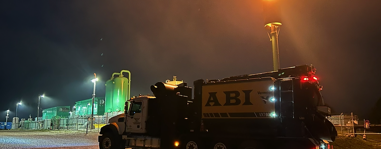 ABI Hydrovac truck working at an illuminated industrial site after dark