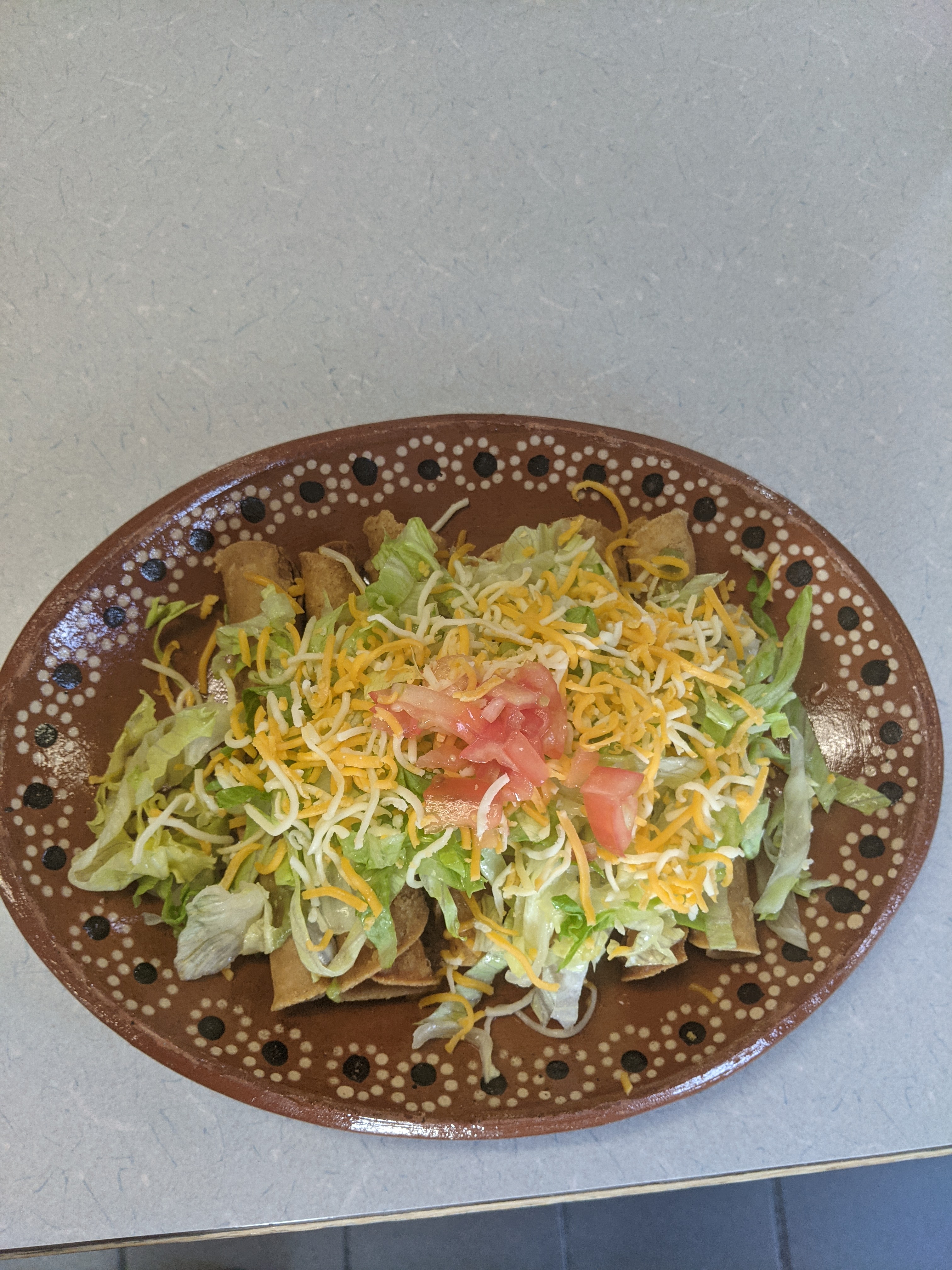 Rolled tacos with guacamole, lettuce and cheese