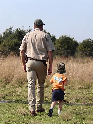 Manie and one of his children walking through a field