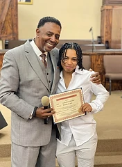 Pastor and young member holding a Certificate of Baptism together