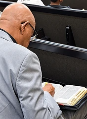 Church member studying and highlighting scripture during service