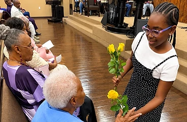 Young girl presenting yellow roses to an elderly woman in the sanctuary