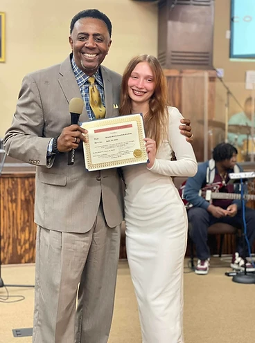 Pastor presenting a Certificate of Baptism to a young woman in a white dress