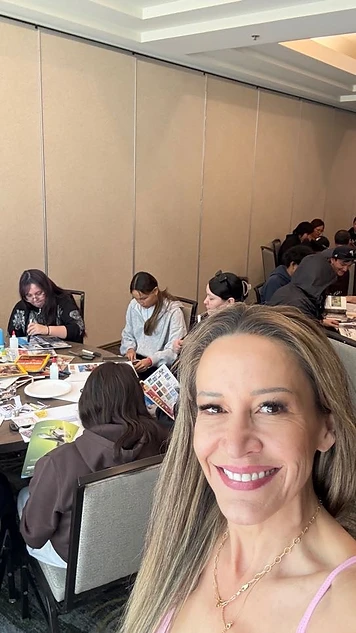 Zandra Ross smiling during a hands-on workshop with participants working around the table