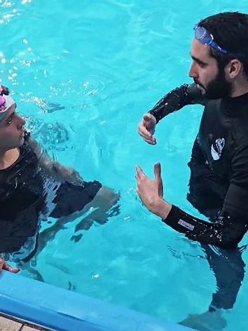 מדריך מדגים טכניקת שחייה לילד במים