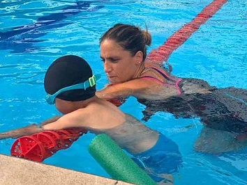 מדריכה תומכת בילד על מצוף בבריכה