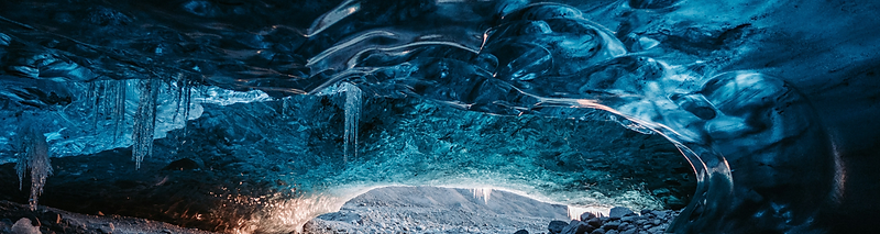 Blue light glowing through an ice cave tunnel in an Icelandic glacier