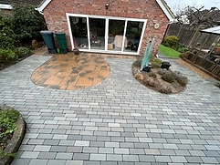 Circular warm-toned stone feature set into grey running-bond paving