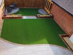 Light-grey porcelain patio with kidney-shaped lawn edged in brick pavers