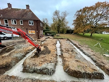Excavated foundation trenches with poured concrete and an excavator