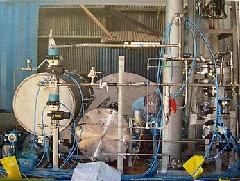 Technician working on a pilot reactor test rig of vessels and steel tubing