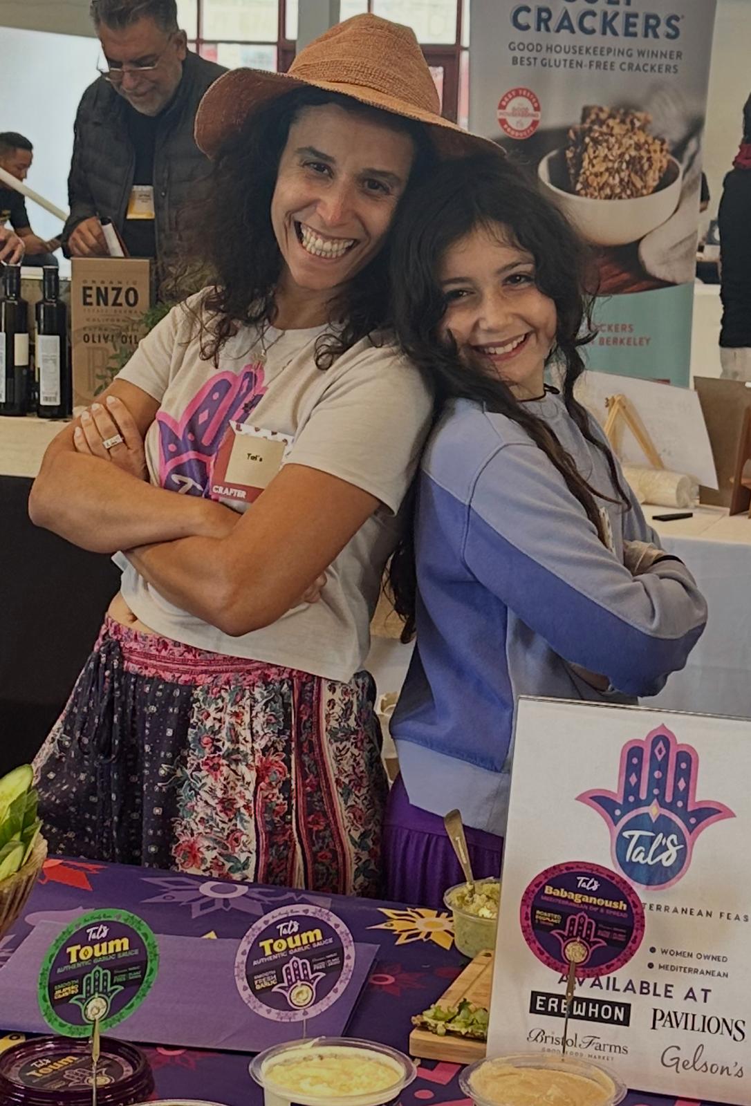 Tal at a market booth with Tal's products