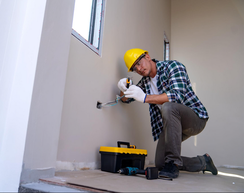 Professional tradesman wiring a room during renovation