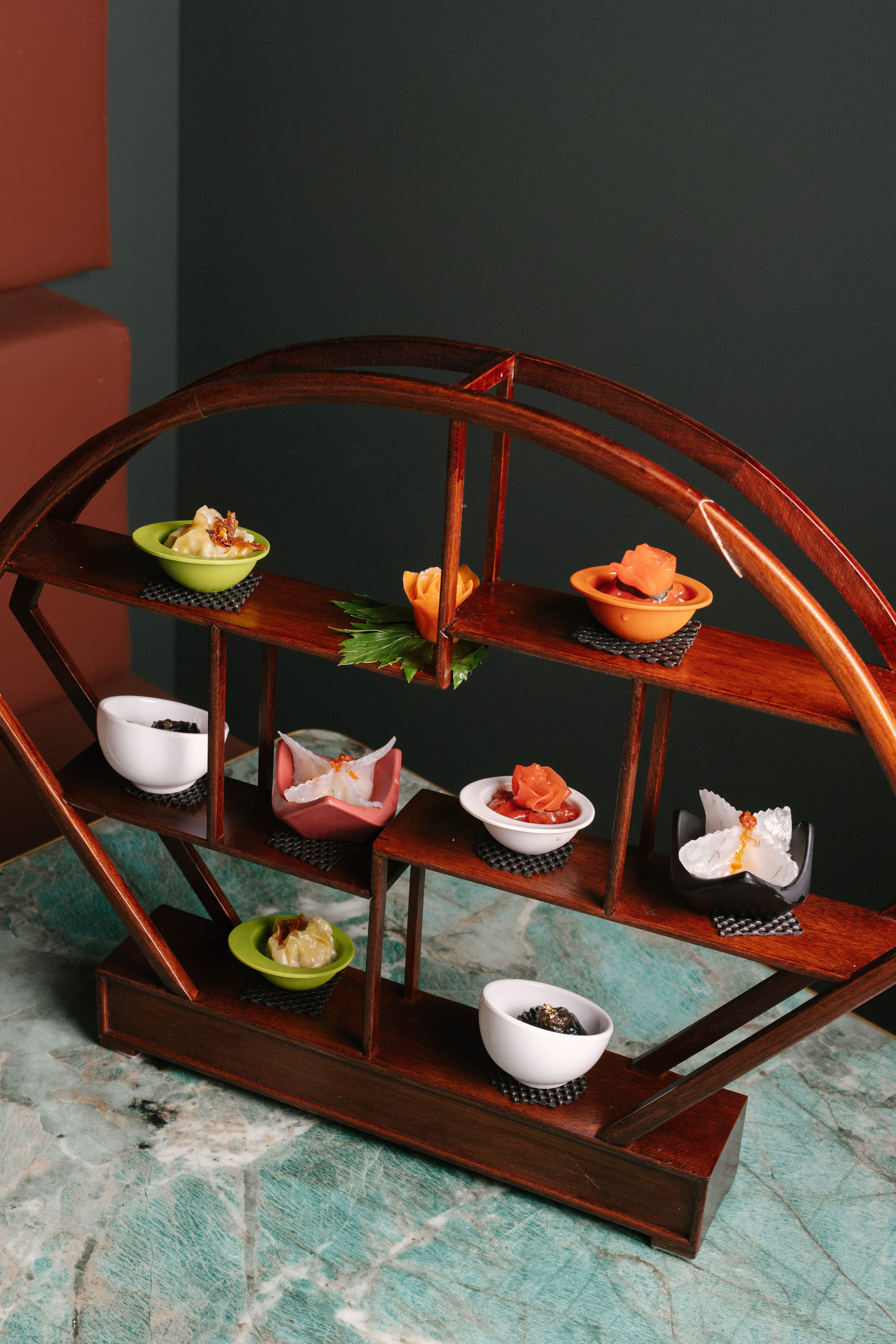 Handgemaakte dim sum gepresenteerd op een donkerhouten étagère bij Restaurant Qin