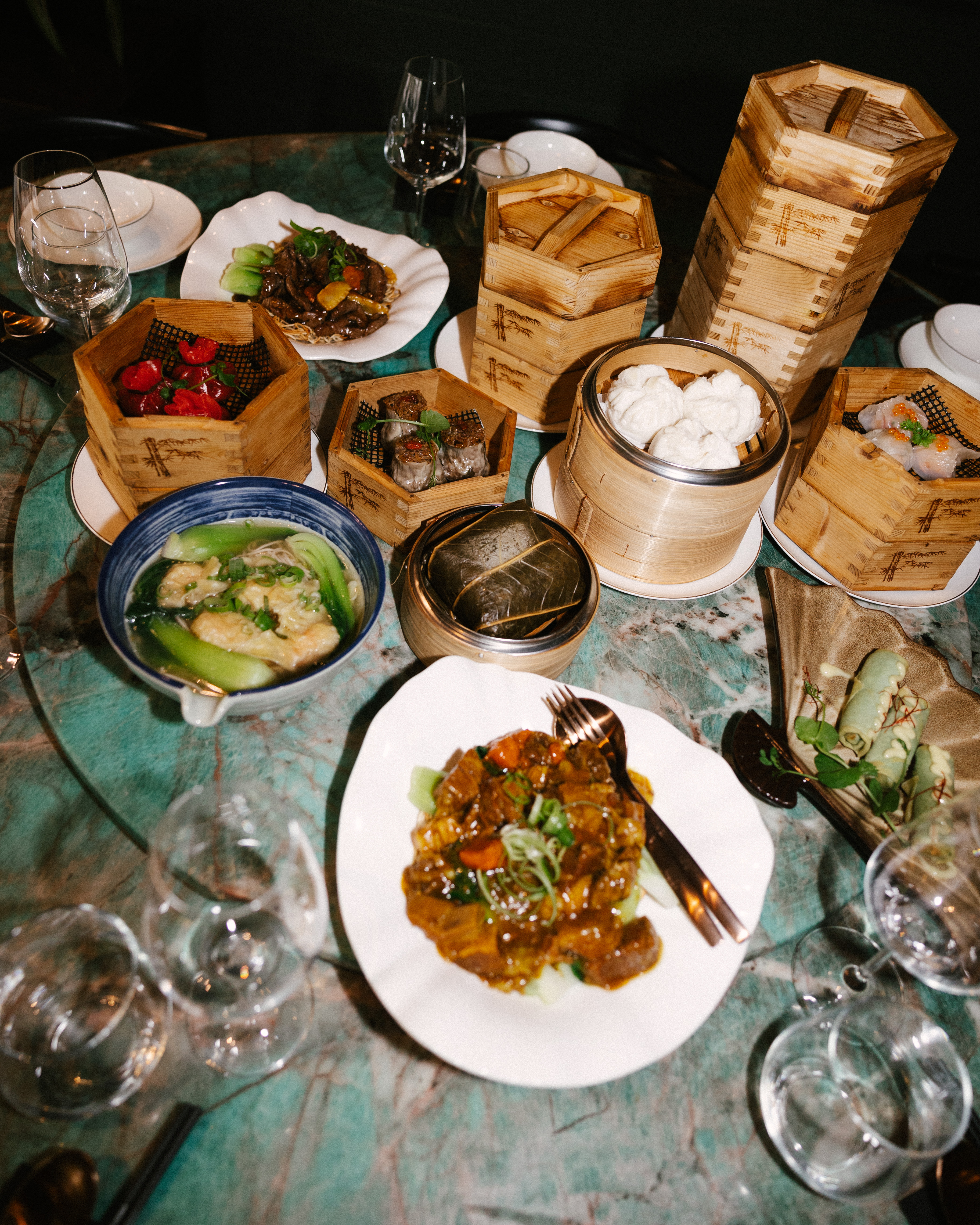 Cantonees groepsmenu met dim sum, soep en wokgerechten op een groene marmeren tafel bij Restaurant Qin