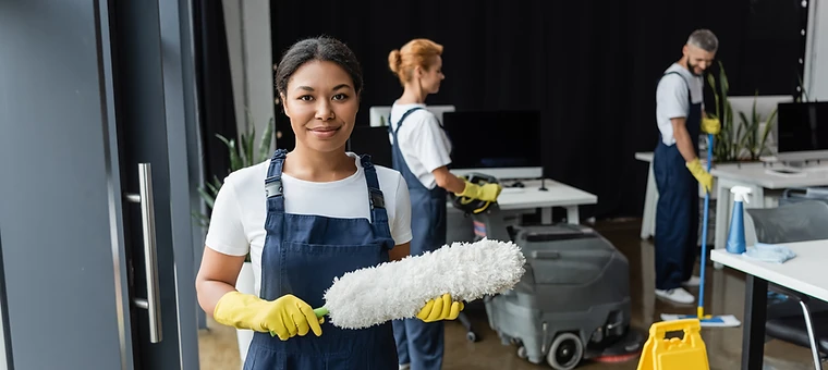 Smiling cleaner posing in a bright modern office during value-based cleaning service.