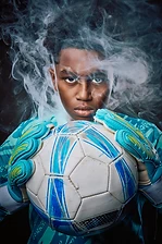 Soccer goalkeeper holding the ball in drifting smoke