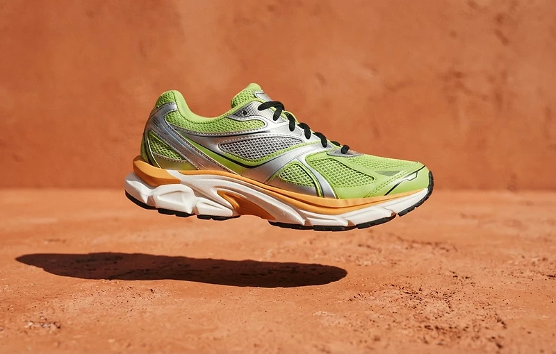 Lime and silver technical running shoes against a bold orange background