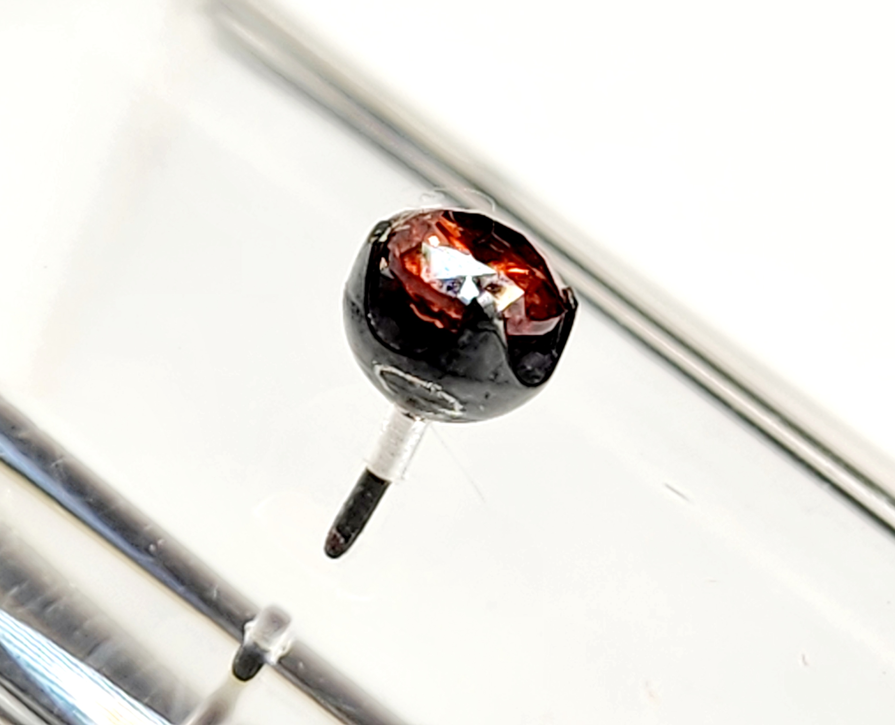 Macro close-up of a faceted garnet gemstone in a dark prong setting, jewelry inspection at Tribal Expression Calgary