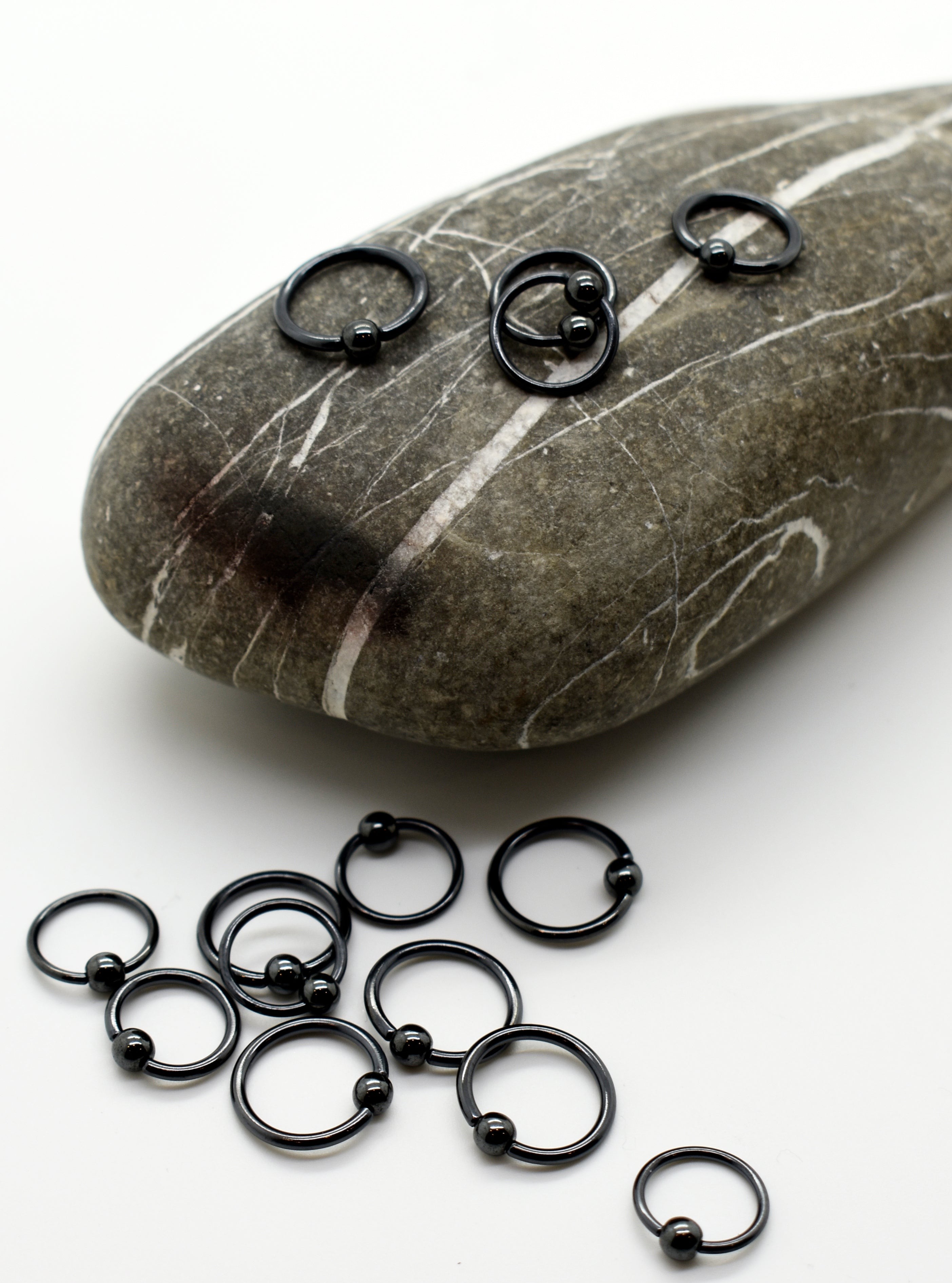 Black niobium captive bead rings arranged on a stone, body jewelry manufactured in Calgary