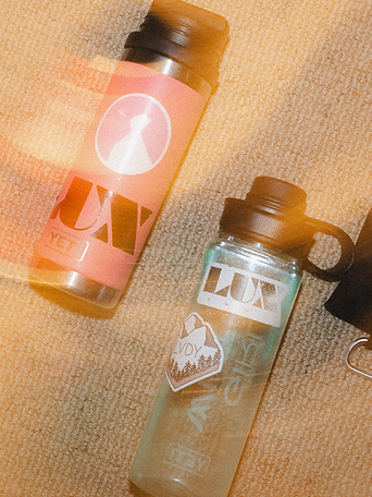 Two clear YETI water bottles with LUX brand stickers resting on a beige carpet
