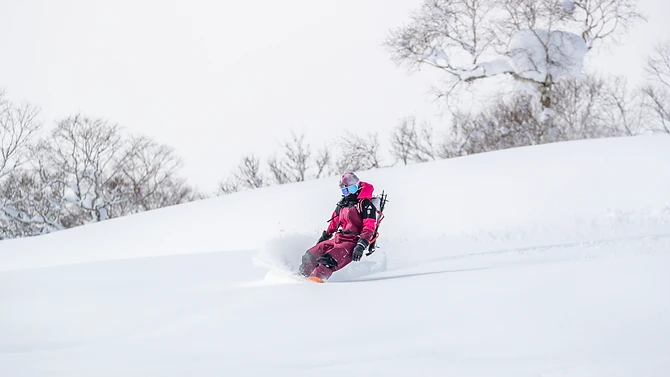 A snowboarder carving a clean turn on an open slope