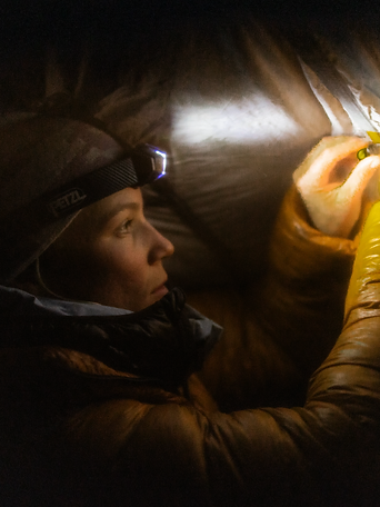 Close-up of a person wearing a Petzl headlamp in low light, adjusting gear