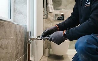 A plumber working on a bathroom radiator