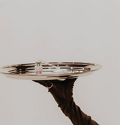 Gloved hand serving a vial and syringe on a silver tray