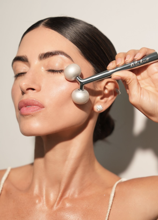 Silver twin-ball facial roller swept up the cheek