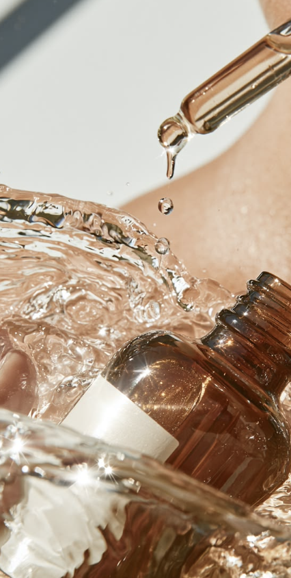 Amber skincare dropper releasing a drop into water