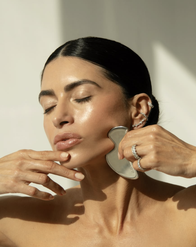 Gua sha tool pressed along the jawline toward the ear