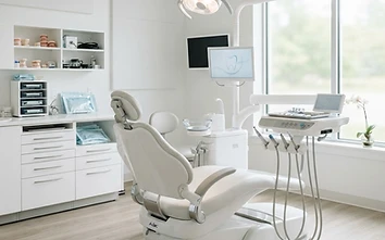 Modern dental exam chair and overhead light in a bright clinic
